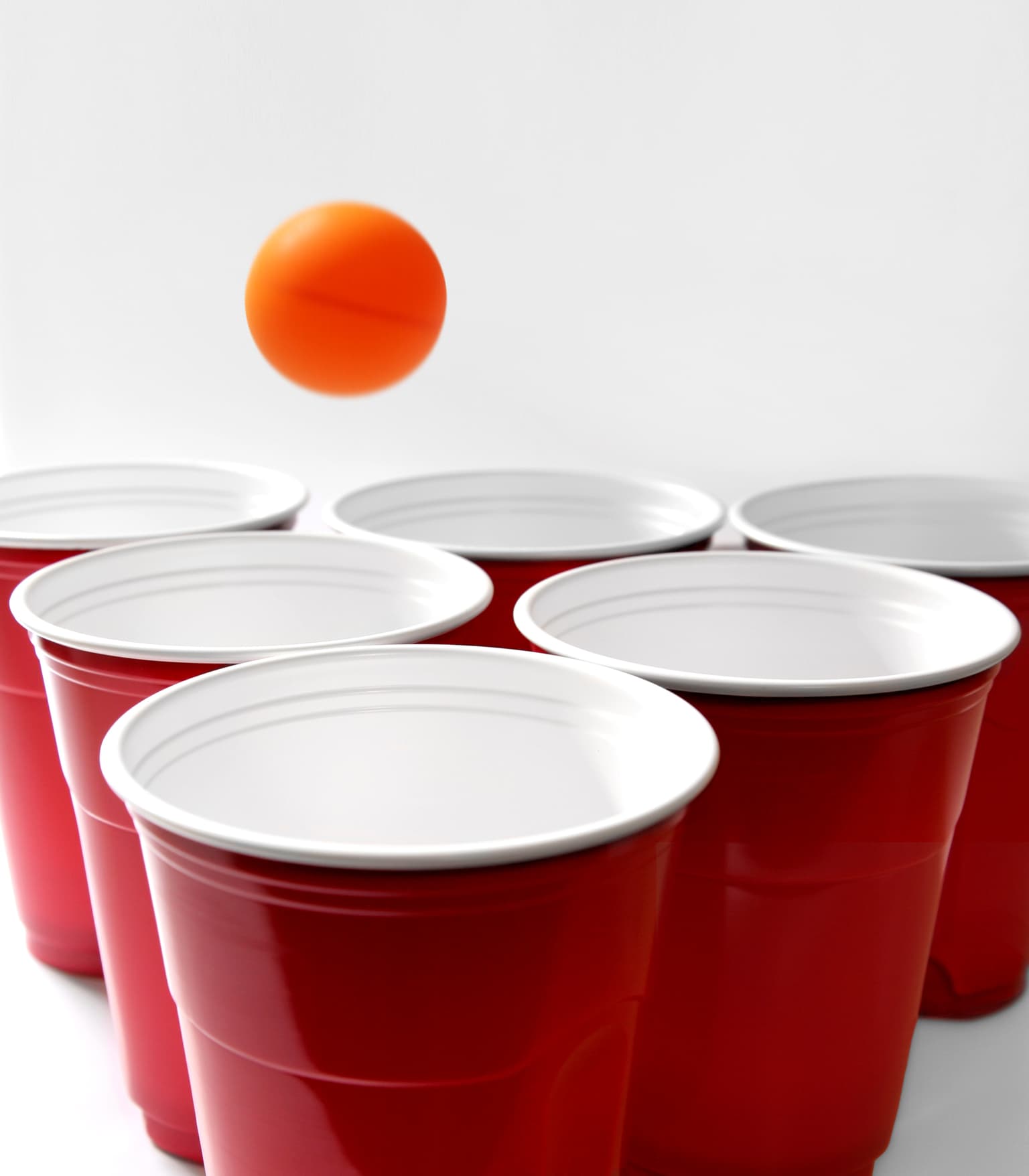 An image of a ping pong ball being thrown into plastic cups.