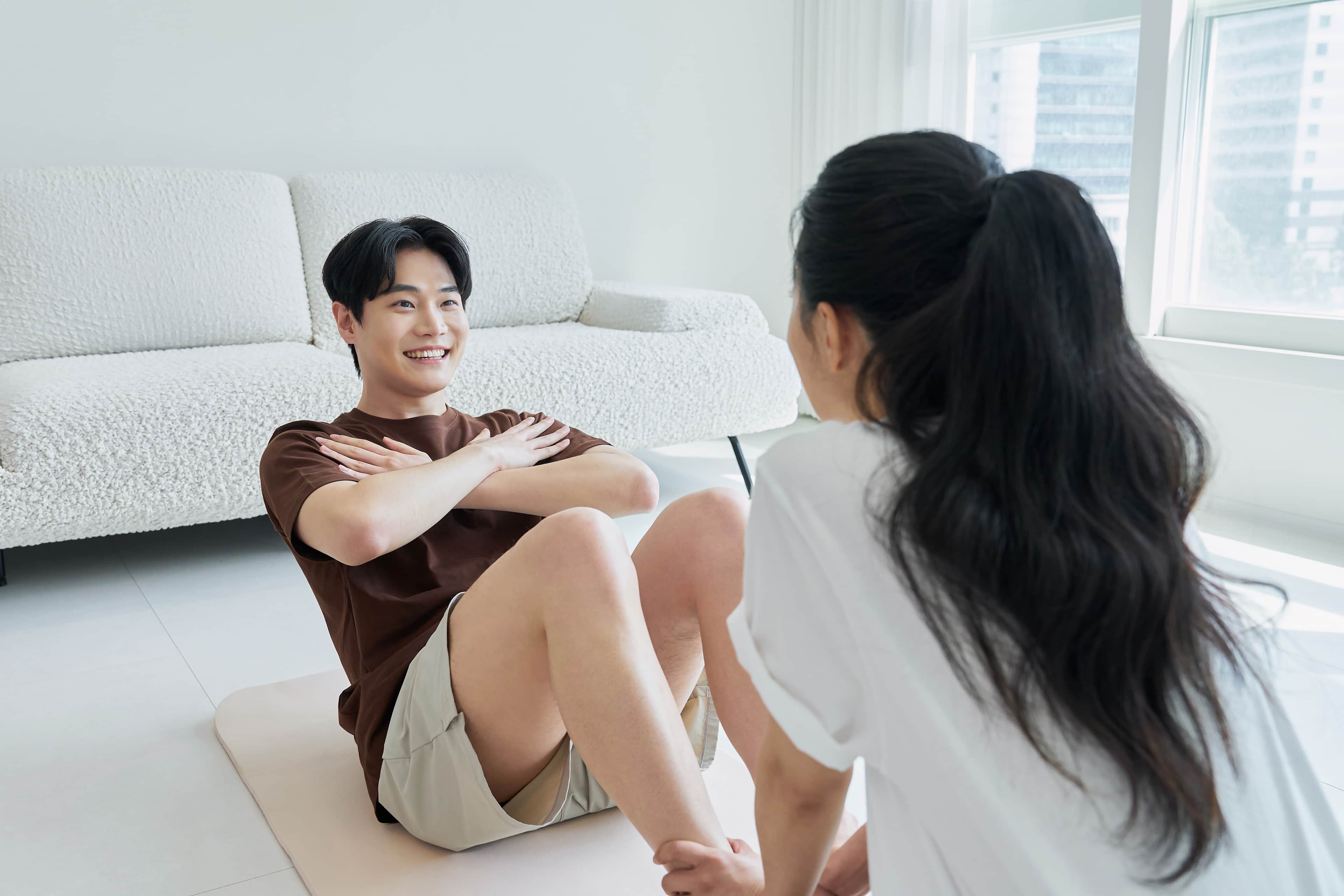 Man doing a sit up with woman holding his feet.