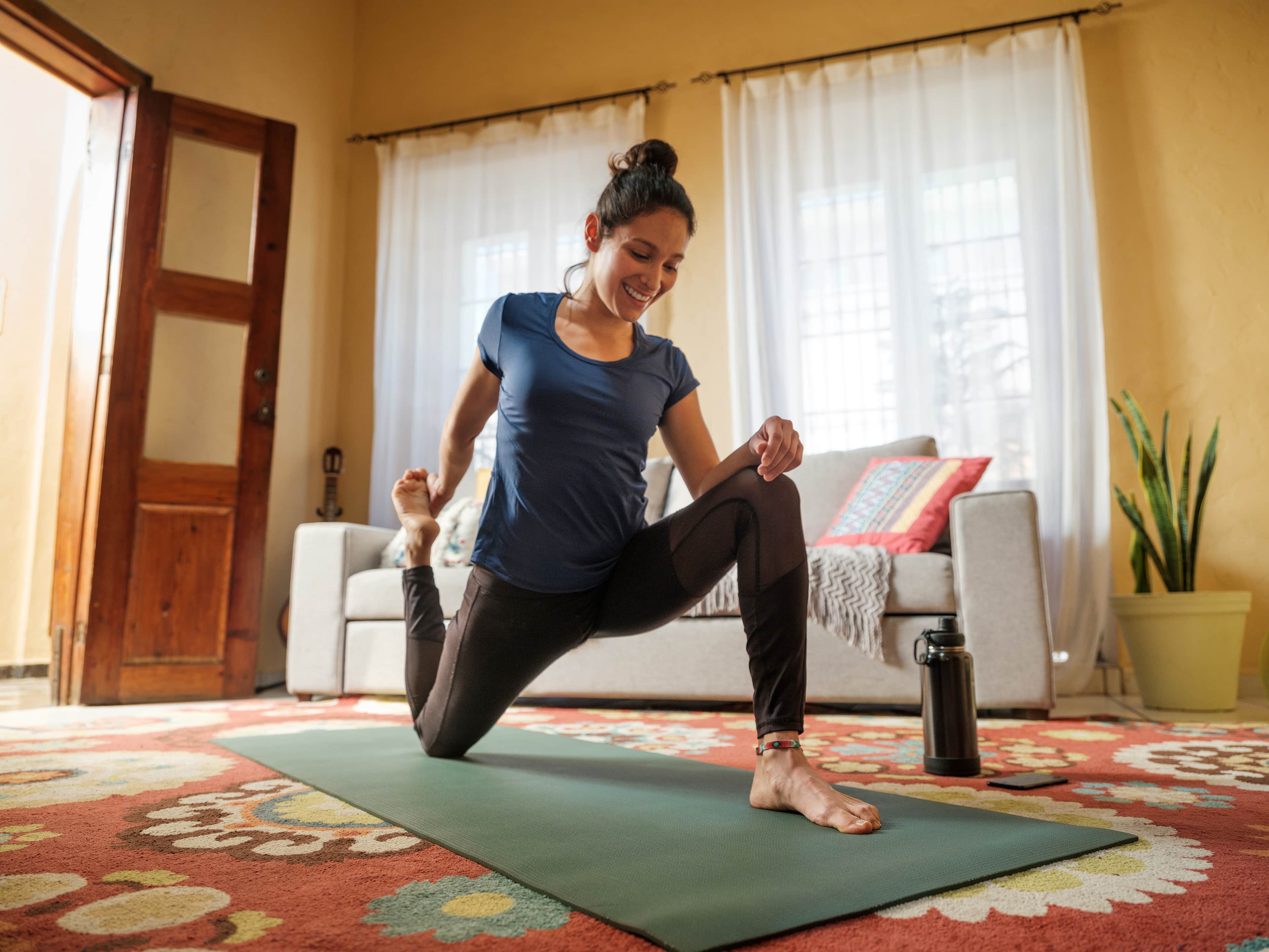 Woman smiling doing a yoga pose on a mat.