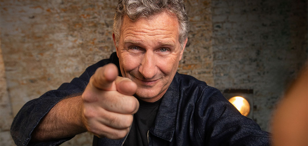 Adam Hills taking a selfie whilst pointing at the camera