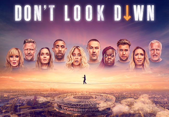 Heads of the cast of Don't Look Down in a line looking concerned with a hire wire over the London stadium below them