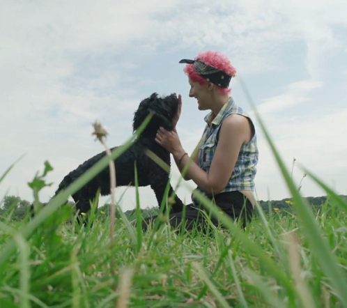 Amanda sitting in field with black dog.