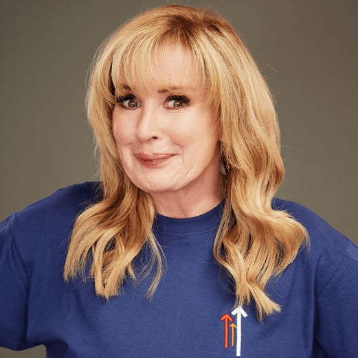 Beverly Callard looking straight ahead smiling wearing a dark blue Stand Up To Cancer t-shirt