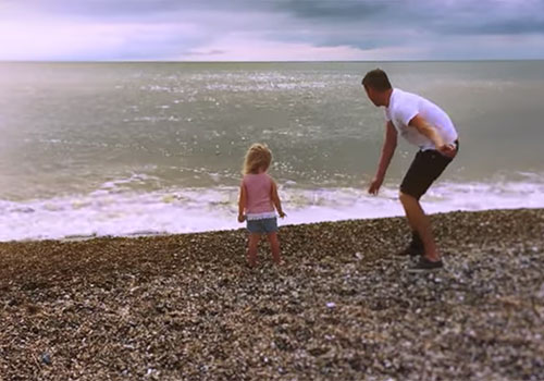 Brett throwing stones into the sea with his daughter.