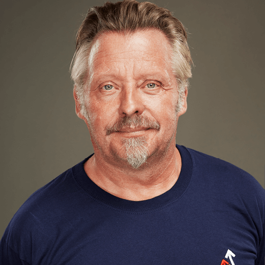 Charley Boorman looking straight ahead wearing a dark blue Stand Up To Cancer t-shirt
