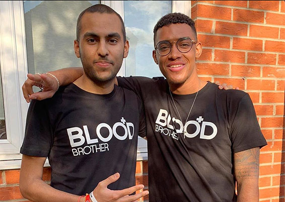 Courtney and Cameron outside a house against a brick wall hugging, wearing Blood Bro's T-shirts together