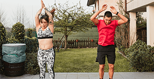 A man and woman doing jumping jacks in the garden