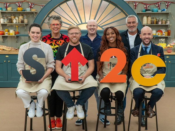 Celebrity Bake Off contestants Daisy Ridley, Rob Beckett, Alexandra Burke and Tom Allen pose with judge Prue Leith, host Mat Lucas, and judge Paul Hollywood. 