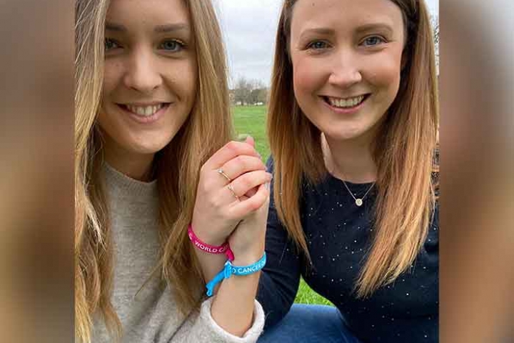 The secondary sisters, Laura and Nicky, holding hands and showing their World Cancer Day Unity Bands