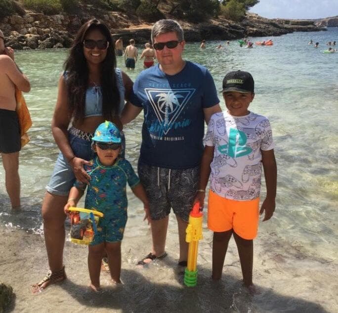 Sherry stands in the sea with her two sons and husband.