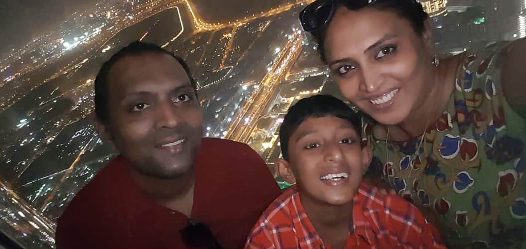 A wife is smiling and posing for the camera with her husband and her young son.