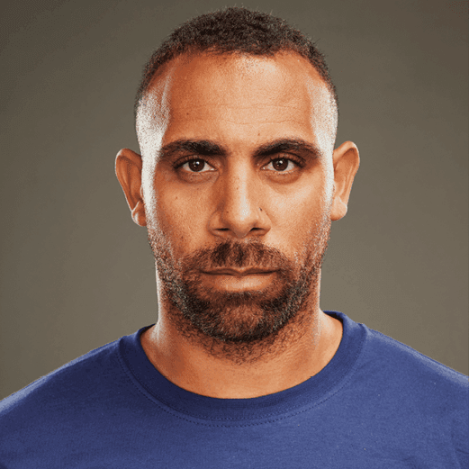 Headshot of Anton Ferdinand in a stand up to cancer t shirt.